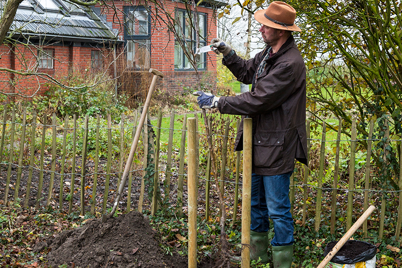 Een man bekijkt wat voor een plantgat hij moet graven